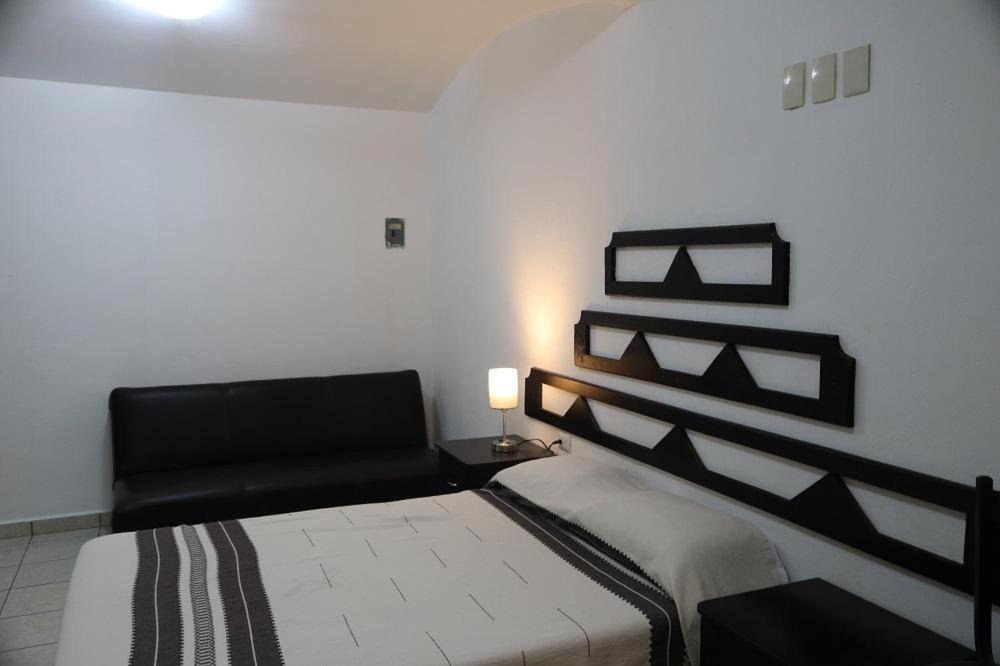 a bedroom with a bed and a black chair at HOTEL CASA BLANCA COEXIST SPACE in Oaxaca City
