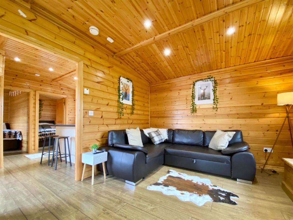 a living room with a leather couch and wooden walls at Pine Lodge - Uk46279 in Camerton