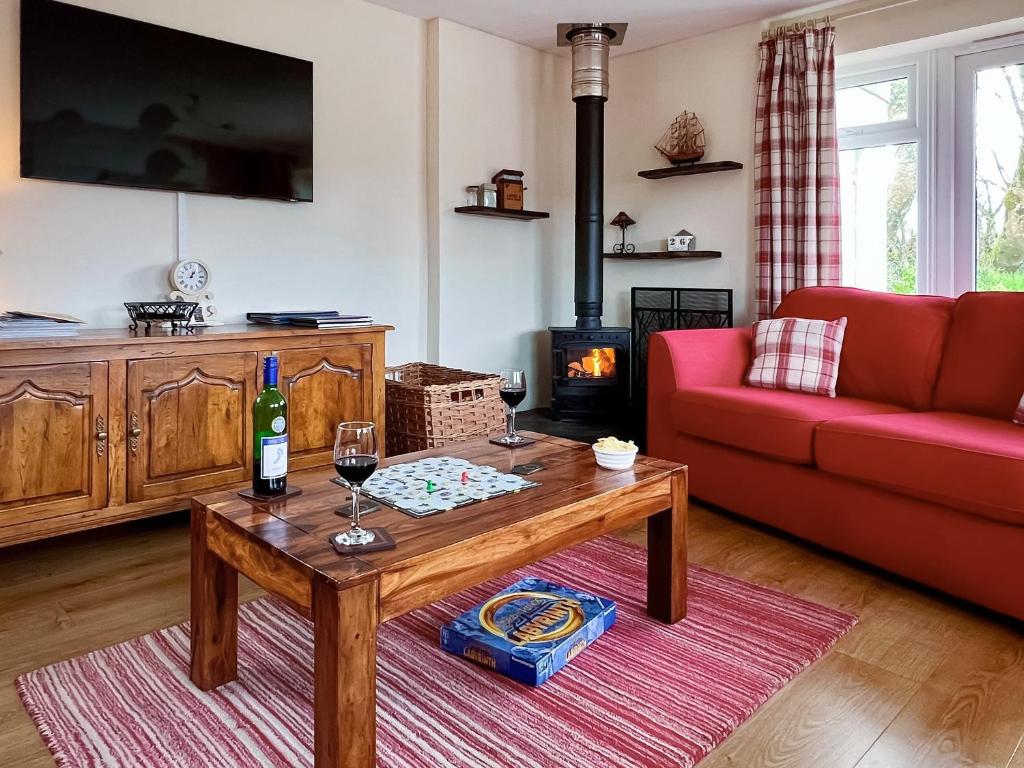 sala de estar con sofá rojo y mesa en Blackberry Cottage, en North Hill