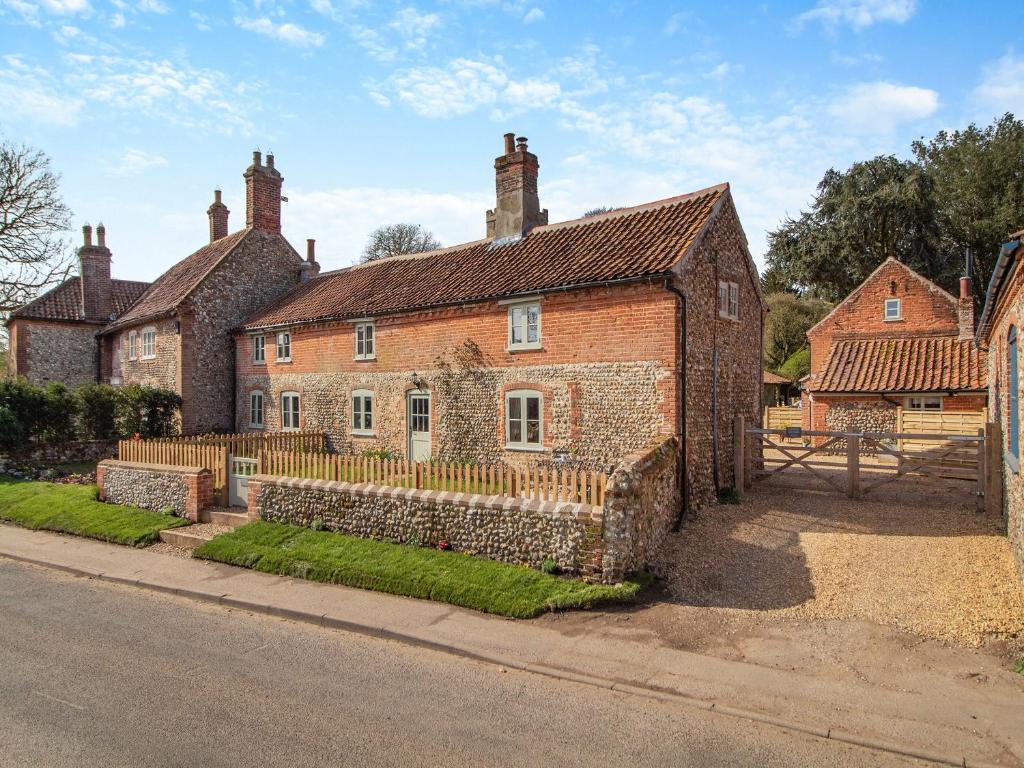 an old brick house with a fence in front of it at Cherry Tree Cottage - Uk30237 in Great Snoring