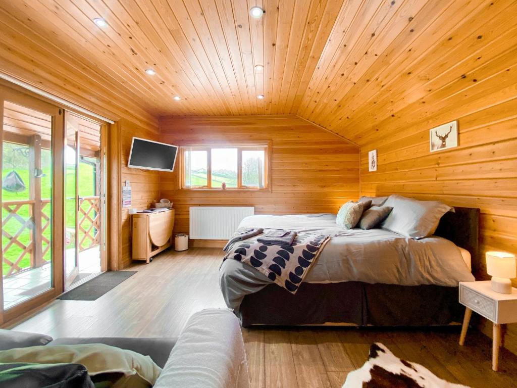 um quarto com uma cama num chalé de madeira em Apple-uk46285 em Camerton