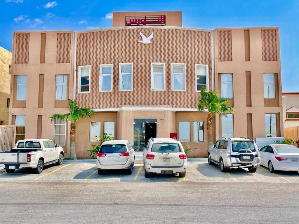 un grupo de autos estacionados en un estacionamiento frente a un edificio en مرفق ضيافة خاص - شقة عائلية, en Al Fayşalīyah