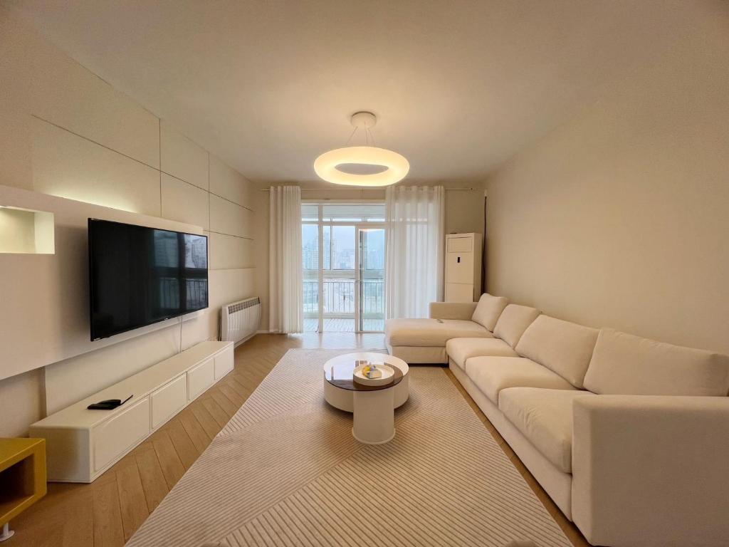 a living room with a white couch and a flat screen tv at Shanghai Jing'an Temple Designer Boutique Large Four Rooms Apartment in Shanghai