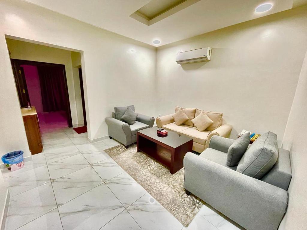 a living room with two couches and a coffee table at مرفق ضيافة خاص - شقة عائلية in Al Fayşalīyah