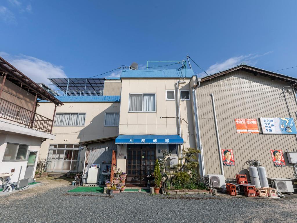 Takekara的住宿－Kawabata Ryokan Takehara by Tabist，白色的建筑,上面有蓝色的遮阳篷