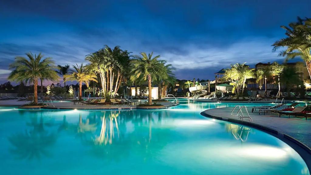 オーランドにあるDisney World ! Pools · BBQ · The Fountain Resort!のヤシの木と青い水が流れる大型プール