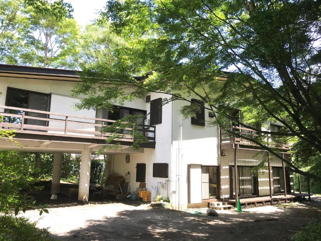 - un bâtiment blanc avec un balcon et des arbres dans l'établissement ～みらい荘～　天然温泉付き一日一組様限定の６４坪広々民泊別荘, à Kirishima