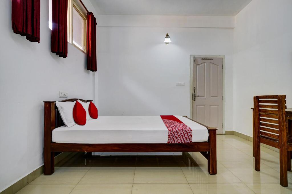 a bedroom with a bed with red pillows on it at OYO Flagship Aruvi Annex in Munnar