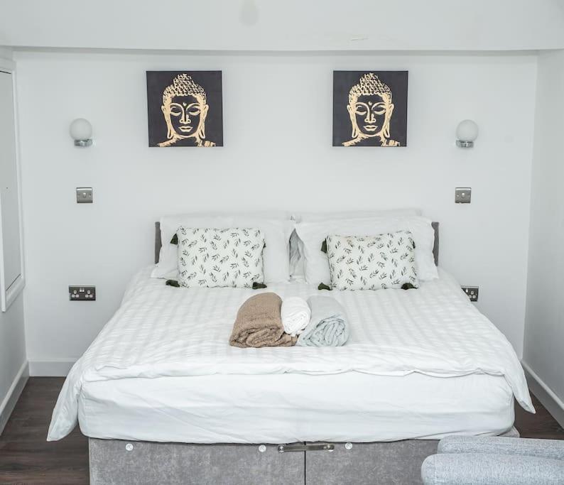 a large white bed with two pictures on the wall at Aylesbury Studio Apartment 6 with parking in Buckinghamshire