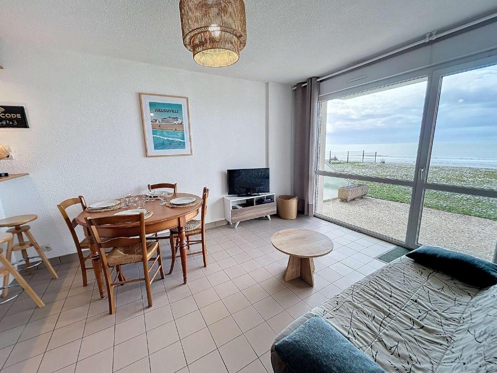 un salon avec une table à manger et une télévision dans l'établissement Joli T2 en front de mer avec accès direct plage, terrasse privative, parking et Wi-Fi gratuit - FR-1-361-45, à Jullouville