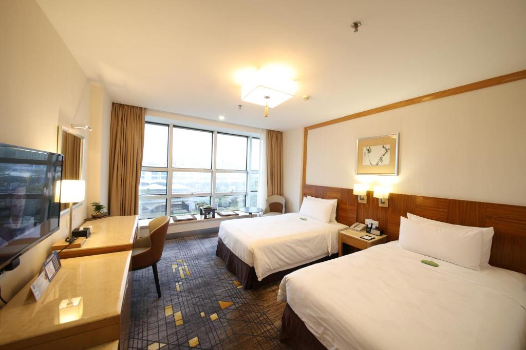 a hotel room with two beds and a flat screen tv at Liuhua Hotel in Guangzhou