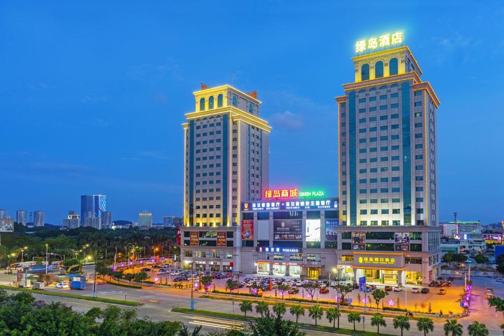 zwei hohe Gebäude in einer Stadt in der Nacht in der Unterkunft Green Island Holiday Hotel in Jiangmen