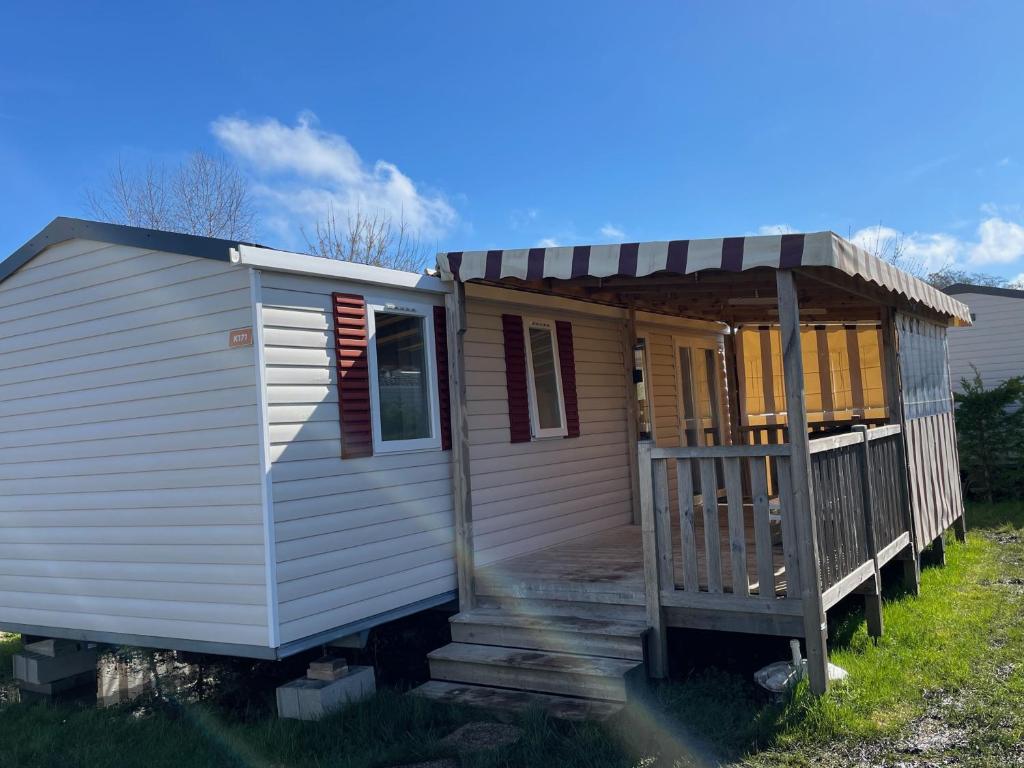a tiny house with a porch and a deck at Mobilhome Ck171 Siblu Les Charmettes in Les Mathes