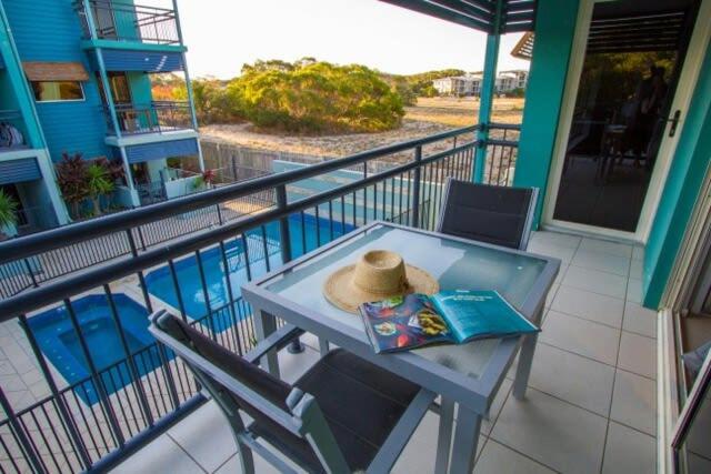 a table with a hat and a book on a balcony at Beach Pad 2 - Modern 2-bed unit by the beach in Agnes Water