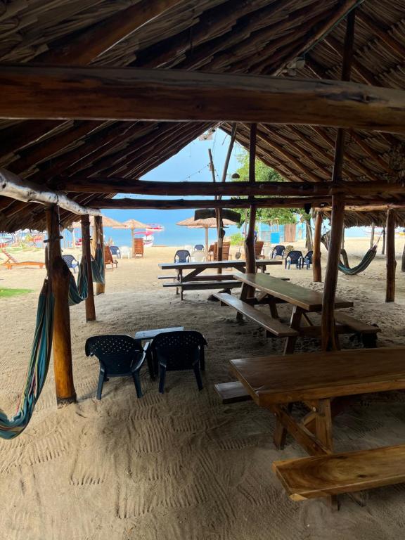 Hostel Beach House في Rincón: مجموعة من الطاولات والكراسي على الشاطئ