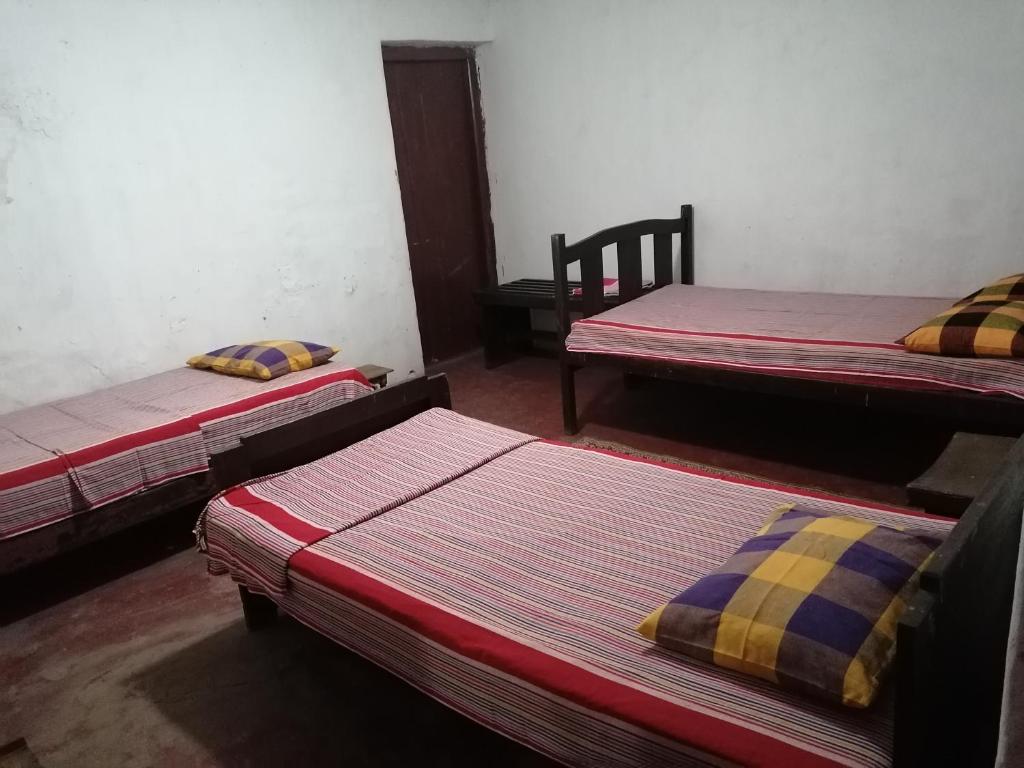 a room with three beds and a chair at The Jungle Life Homestay Thangamalay Sanctuary Haputale by Gisela Sivam in Haputale