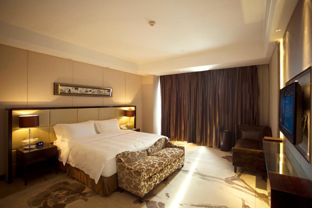 ein Hotelzimmer mit einem Bett und einem Stuhl in der Unterkunft Howard Johnson Changsheng Plaza Meizhou in Meizhou