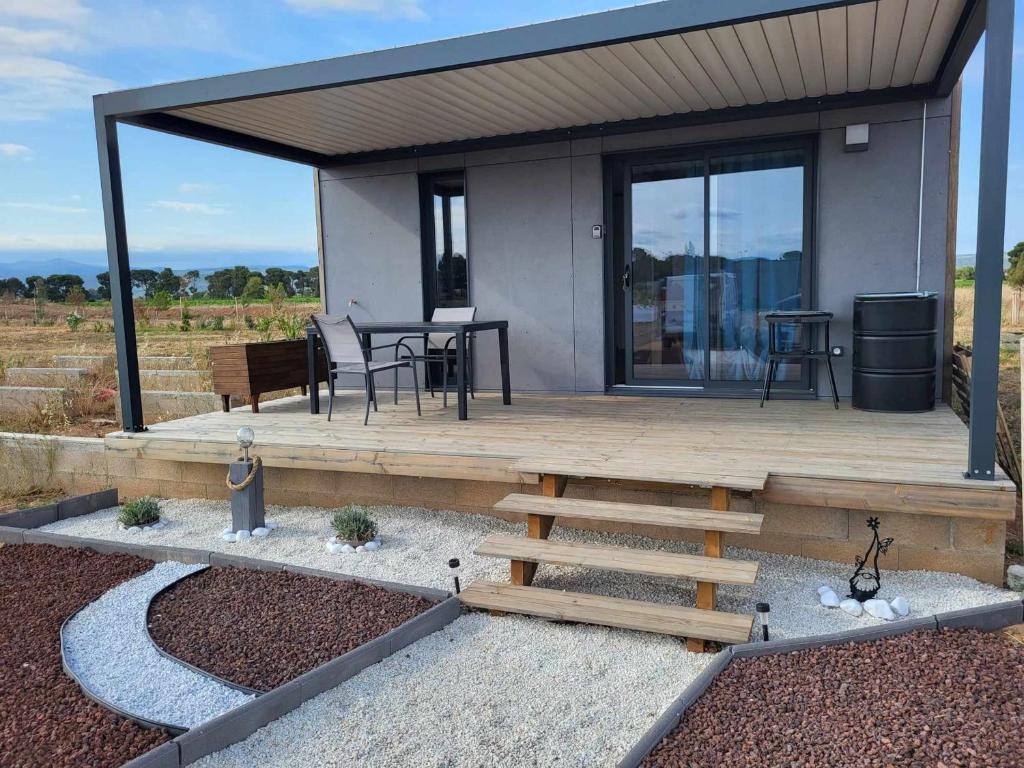 une maison avec une terrasse en bois et une table dans l'établissement Charmant Chalet 2 Chambres avec Terrasse à 100m du Lac de Jouarres, Piscine Chauffée, Climatisation - FR-1-783-8, à Olonzac