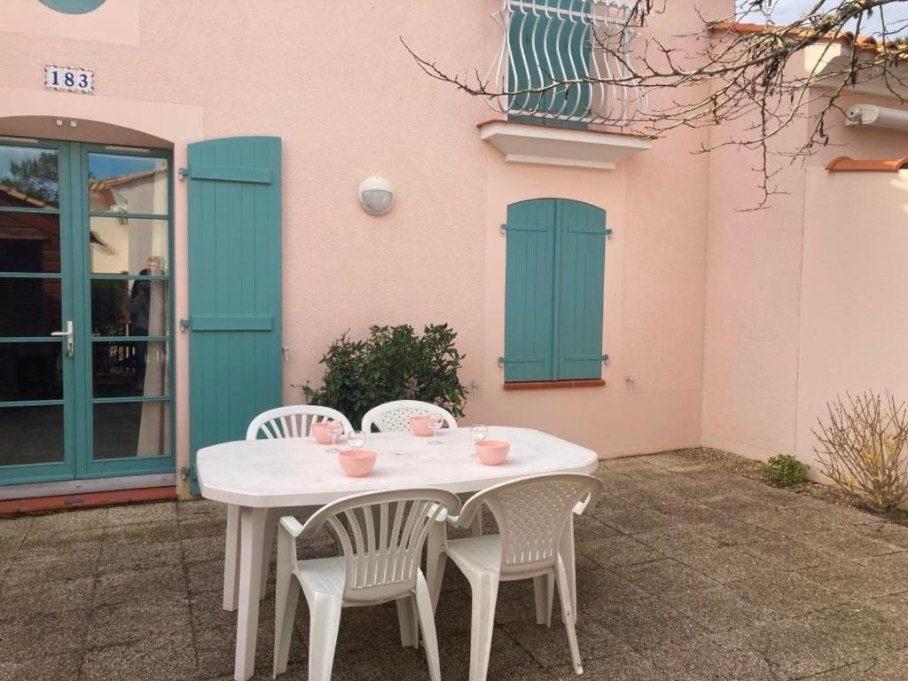 une table et des chaises blanches devant un bâtiment dans l'établissement Maison avec piscine, proche forêt et plage à Saint Jean de Monts - FR-1-323-527, à Saint-Jean-de-Monts
