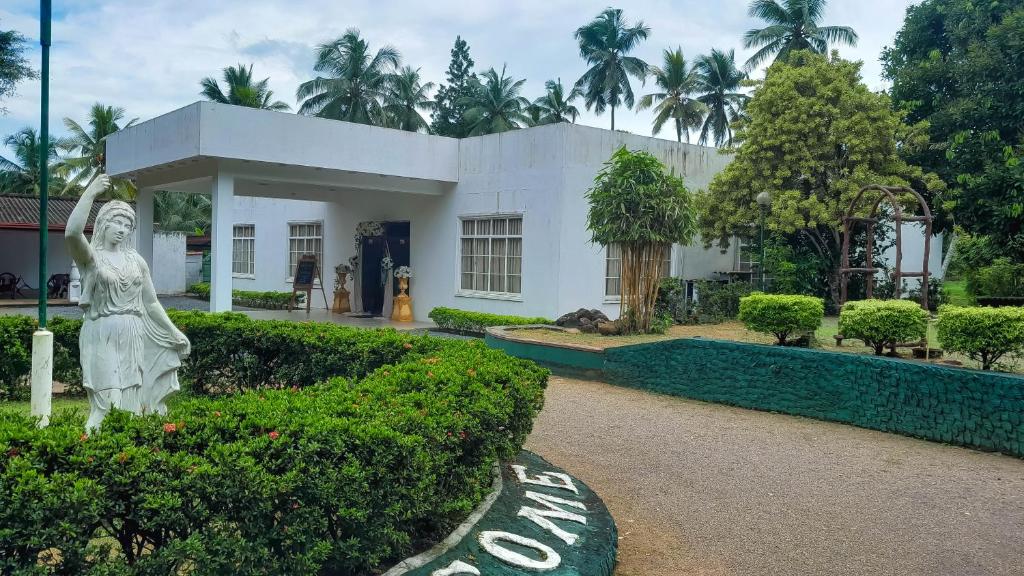 a white building with a statue in front of it at Hotel Pugoda Village in Pugoda