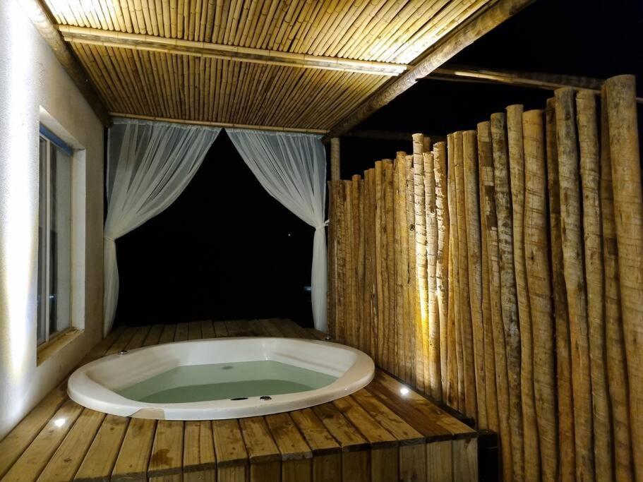 une baignoire jacuzzi dans une chambre avec des murs en bois dans l'établissement Casa do Descanso com jacuzzi em Igaratá, à Igaratá