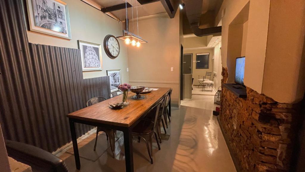 a dining room table with chairs and a clock on the wall at PH Palermo HollyHouse in Buenos Aires