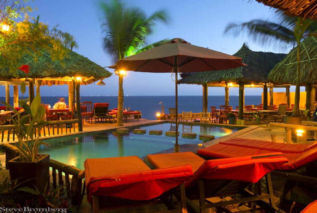 美奈的住宿－喬伊咖啡廳&花園度假酒店，一个带椅子和遮阳伞的游泳池以及大海