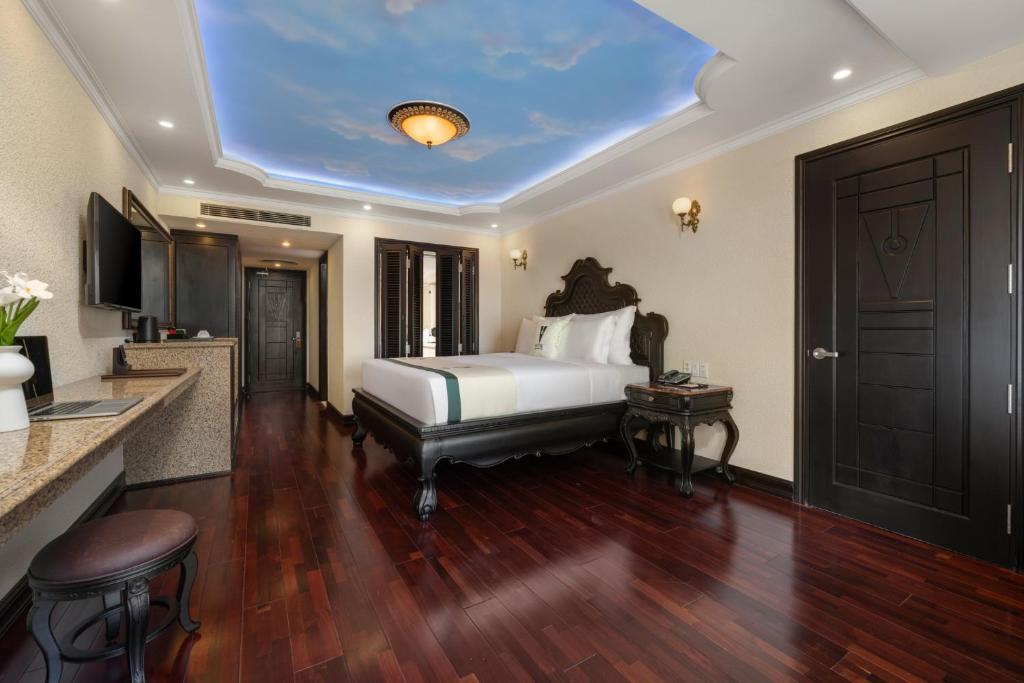 A formal bedroom with a central carved bed, glossy wood floor and compact counter workspace.