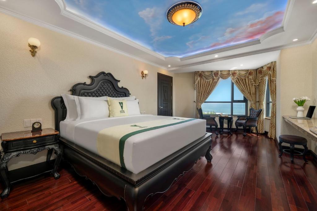 A traditionally styled bedroom with a carved bed, painted ceiling and city-facing window.
