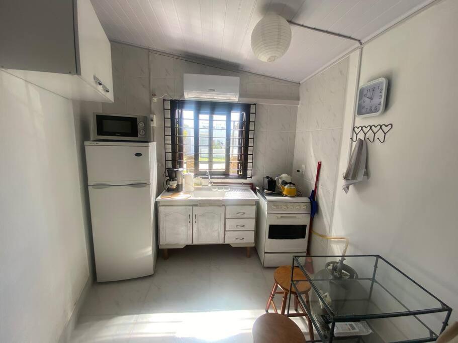 uma cozinha branca com um lavatório e um frigorífico em Parada y relax en Alvorada, Barra do Chui em Xuí