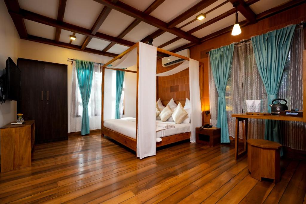 a bedroom with a canopy bed with blue curtains at Little Chembaka in Kumarakom