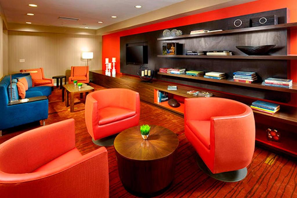 a living room with orange chairs and a television at Courtyard by Marriott Akron Stow in Stow
