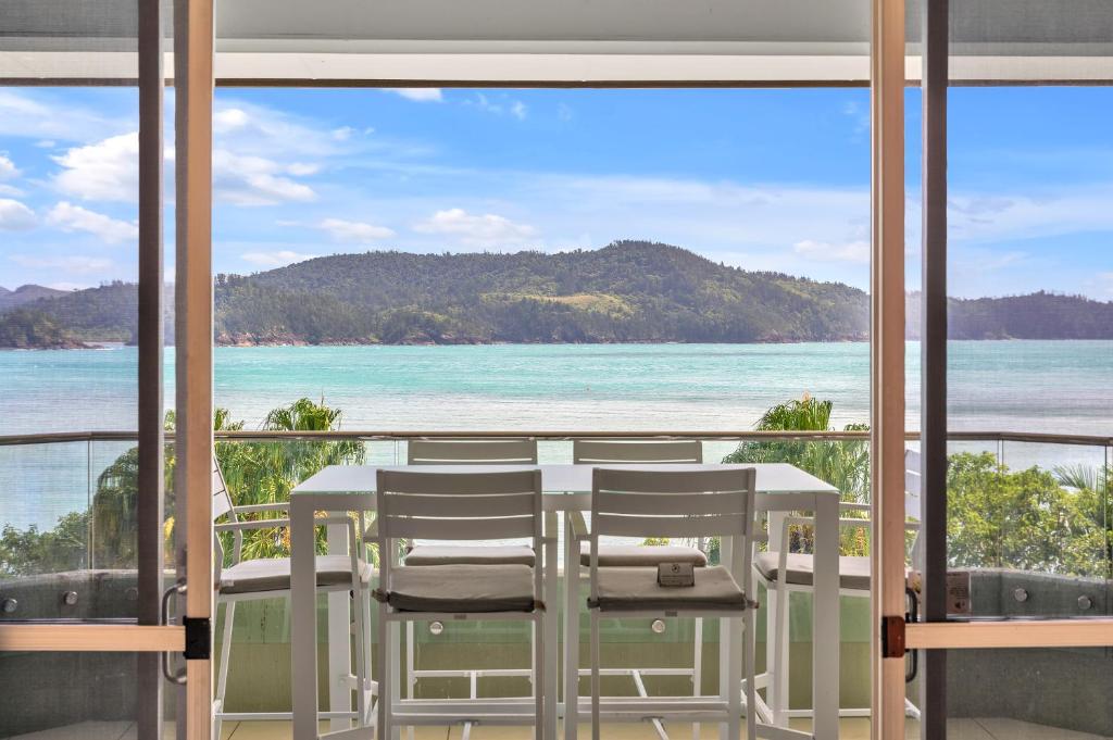 a view of the ocean from a room with a table and chairs at Lagoon Beachfront Lodge 206 on Hamilton Island by HamoRent in Hamilton Island