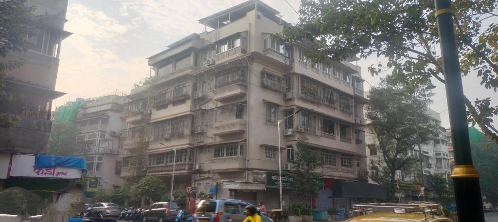 um edifício branco alto numa rua da cidade com trânsito em Bed and Breakfast at Colaba em Mumbai
