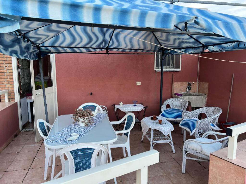 un patio con mesas y sillas bajo una sombrilla azul en Da Giusy a marzamemi, en Pachino