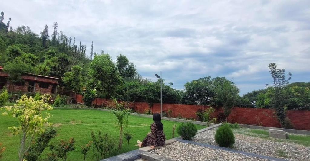een vrouw op een bankje in een tuin bij Airport Forest View Ghugugti Farmstay in Dehradun