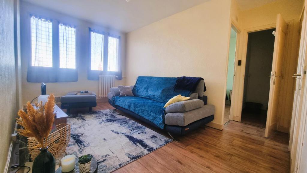 ein Wohnzimmer mit einem blauen Sofa und einem Stuhl in der Unterkunft Appartement entier de 40 m2 proche gare Auterive in Auterive