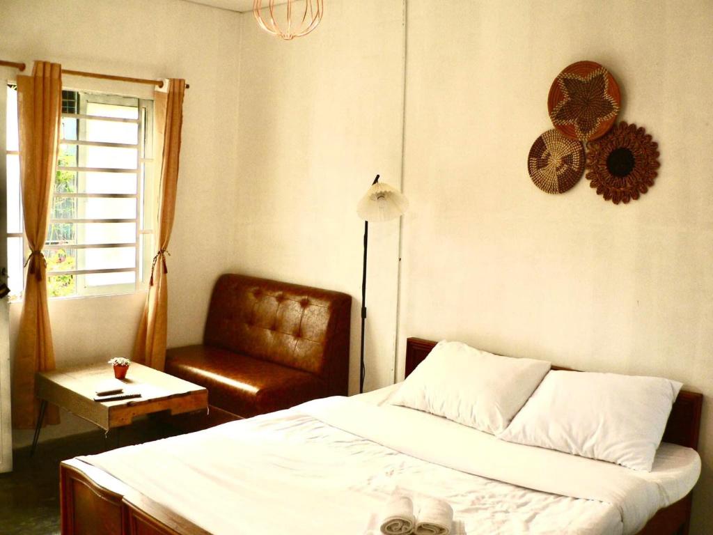 een slaapkamer met een bed, een stoel en een raam bij Yang Homestay B&B in Ho Chi Minh-stad
