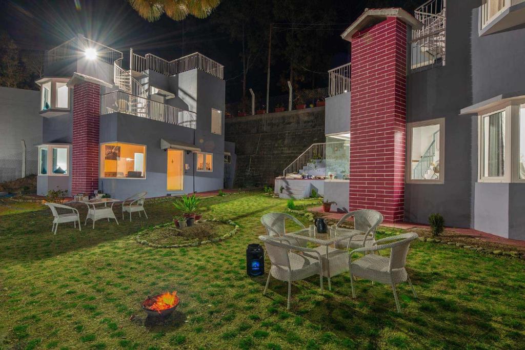 um pátio com mesas e cadeiras num quintal à noite em StayVista at Pines & Spruce - Exclusive getaway em Lansdowne