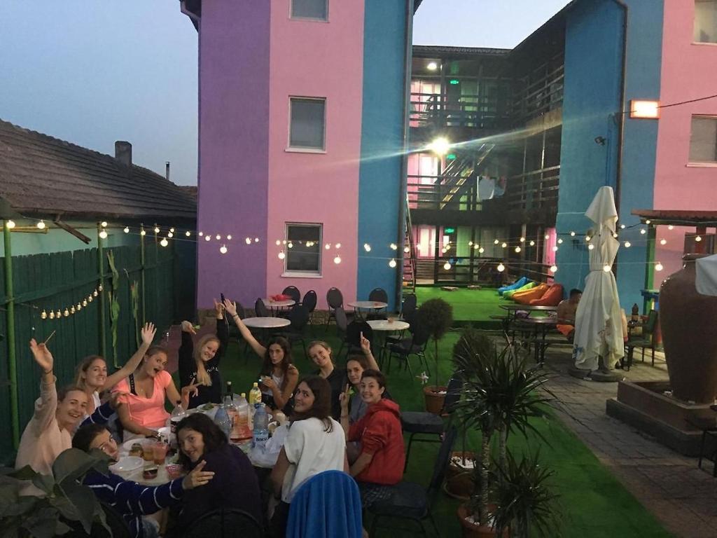 un grupo de personas sentadas en una mesa con las manos en alto en Hostel Flamingo Costinesti en Costinesti