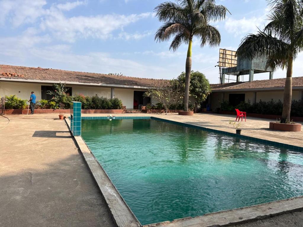 ein Pool vor einem Haus mit Palmen in der Unterkunft Hotel Sai Plaza in Igatpuri