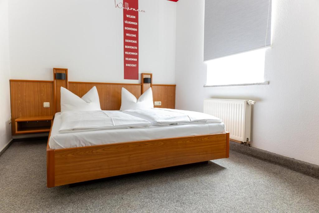 a bedroom with a bed with white sheets and a window at Hotel Anker in Saalfeld