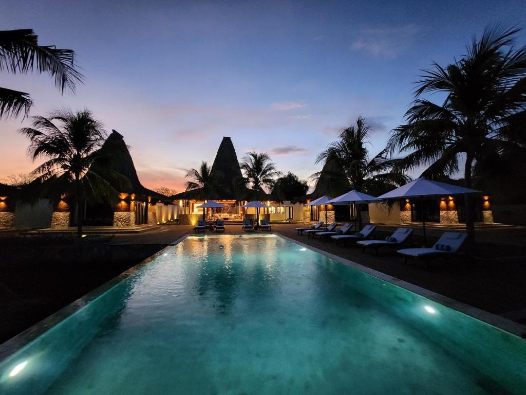 a swimming pool with chairs and umbrellas at night at KANDORA Luxury villas in Maujawa