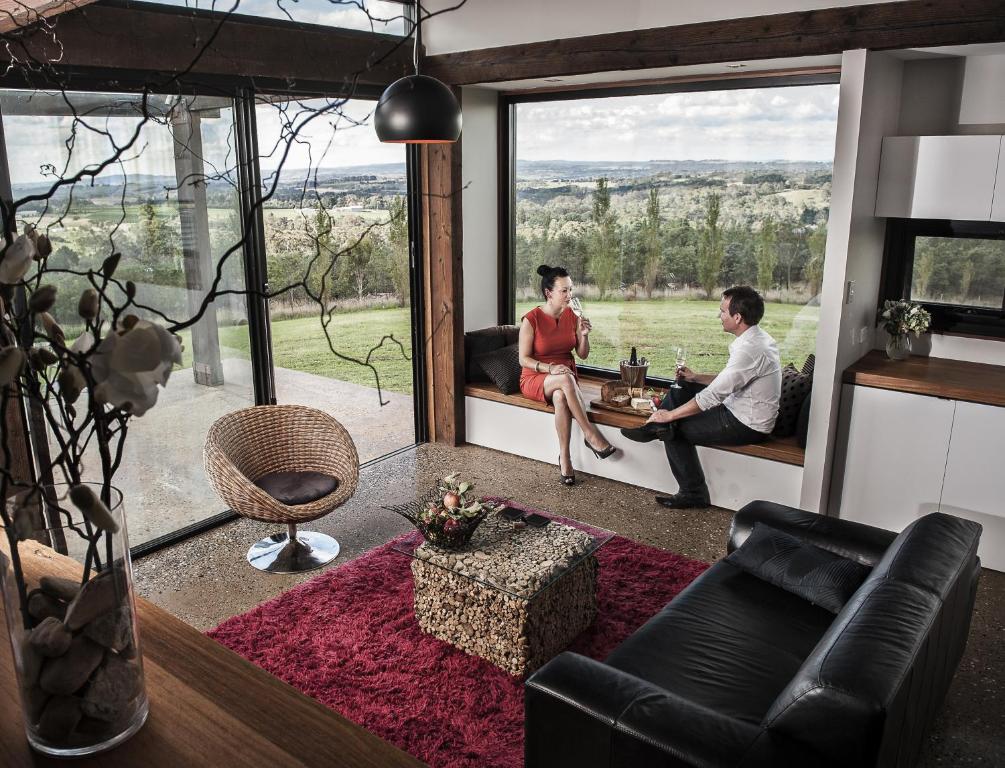 Ein Mann und eine Frau sitzen in einem Wohnzimmer mit Fenster in der Unterkunft Borrodell Vineyard in Orange