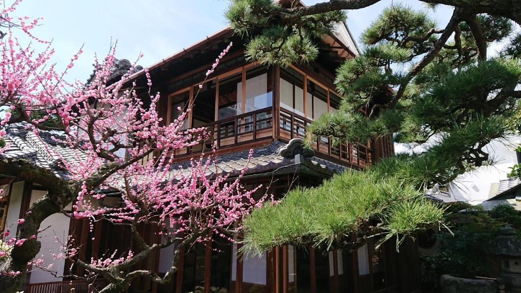 una casa con flores rosas delante de ella en 蔵の宿　櫻林亭, en Miwa