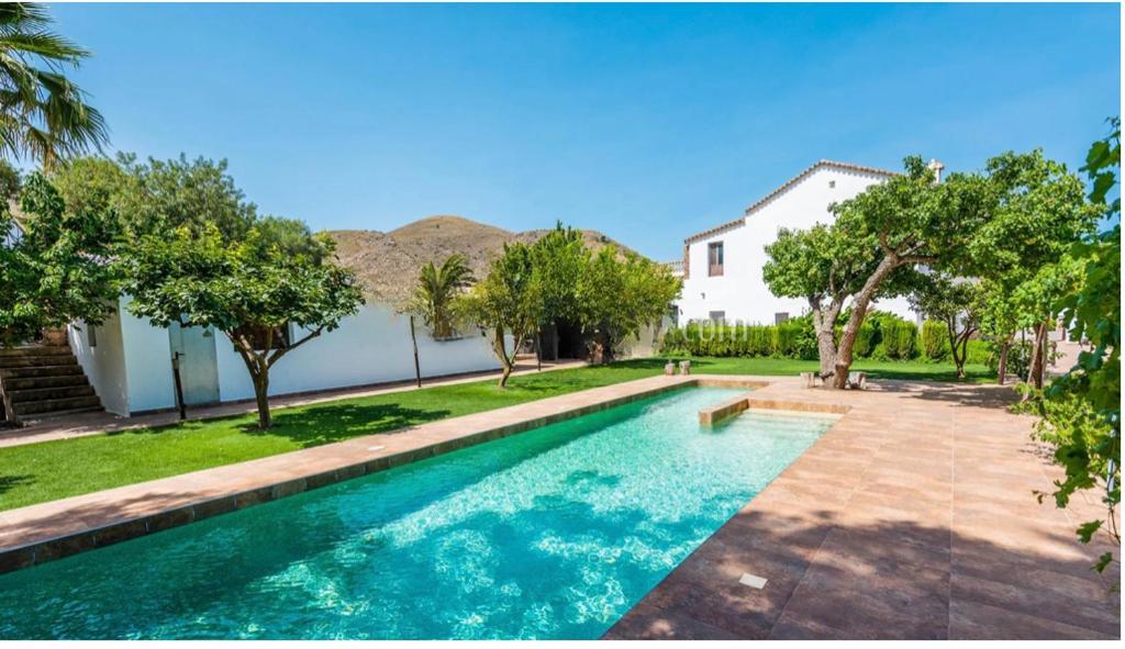 a swimming pool in front of a house at Cortijo Andaluz Doña Adela in Almería