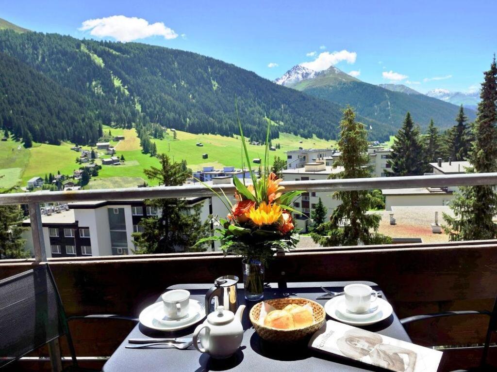 a table with a vase of flowers on top of a balcony at - fantastic mountain panorama in Davos