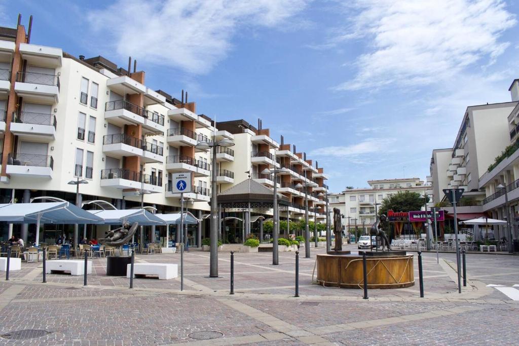 een stadsplein met gebouwen, tafels en parasols bij Piazza Marconi Attico Duplex per 5 persone in Lido di Jesolo