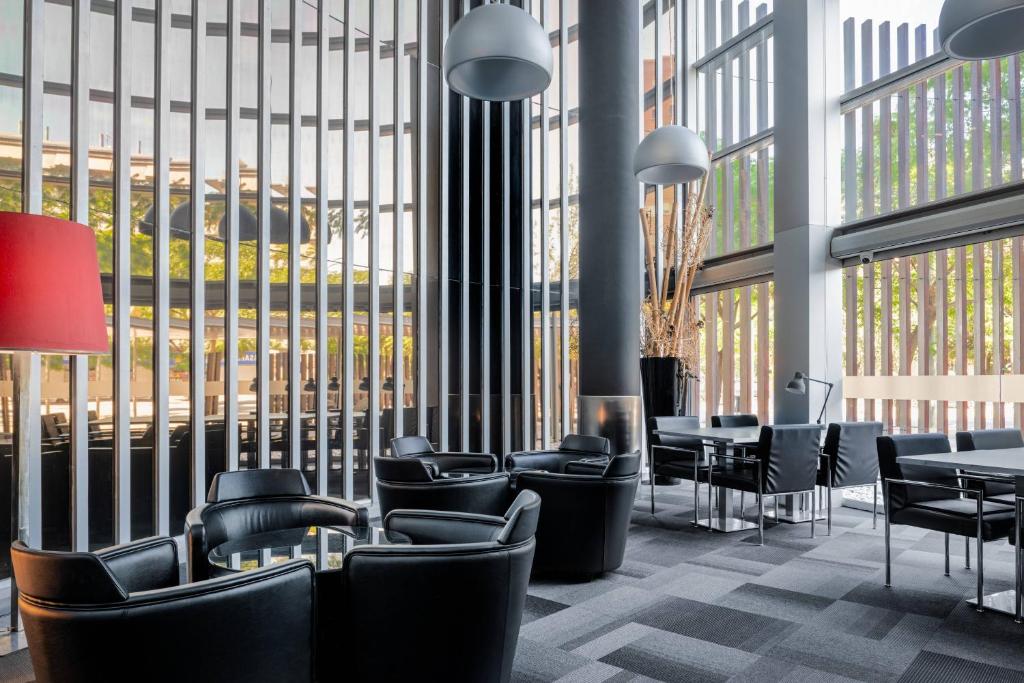 a lobby with chairs and tables and large windows at AC Hotel Som by Marriott in Hospitalet de Llobregat