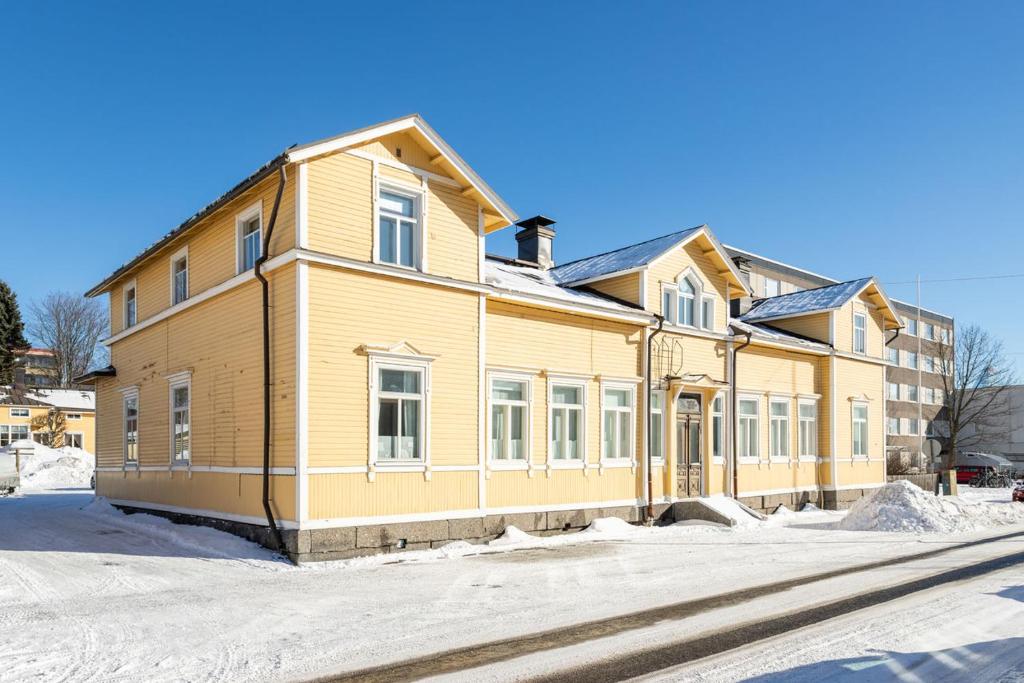 Una gran casa amarilla con nieve en el suelo en Idyllinen puutaloasunto en Vaasa